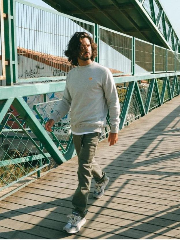 A man walking and wearing Trendsplant clothes, grey sweater and green pants