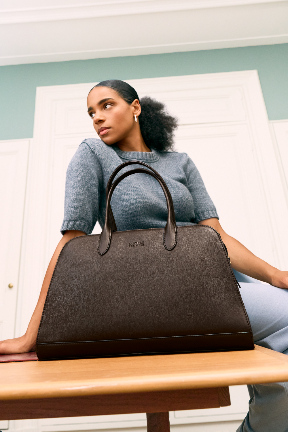 Woman standing outside in nature with o my bag cognac brown shoulder bag