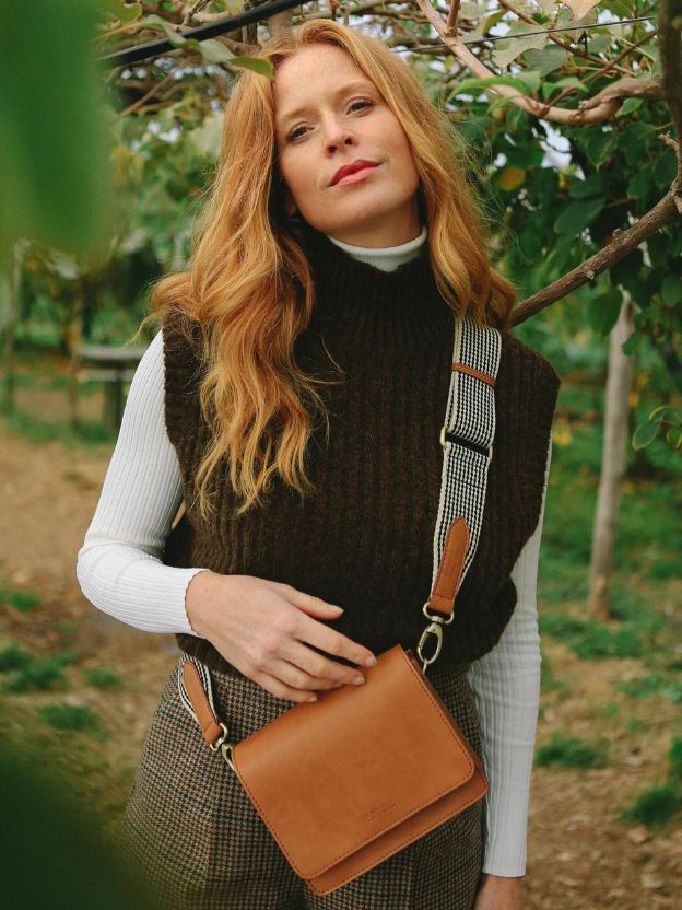 Woman standing outside in nature with o my bag cognac brown shoulder bag