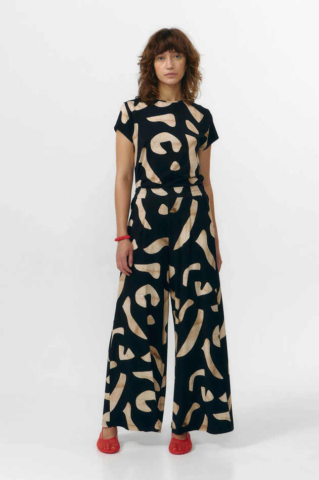 Woman wearing a black and beige patterned jumpsuit on a white background