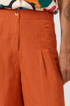 Close-up of orange pants with a colorful shirt and tattooed arm in the background