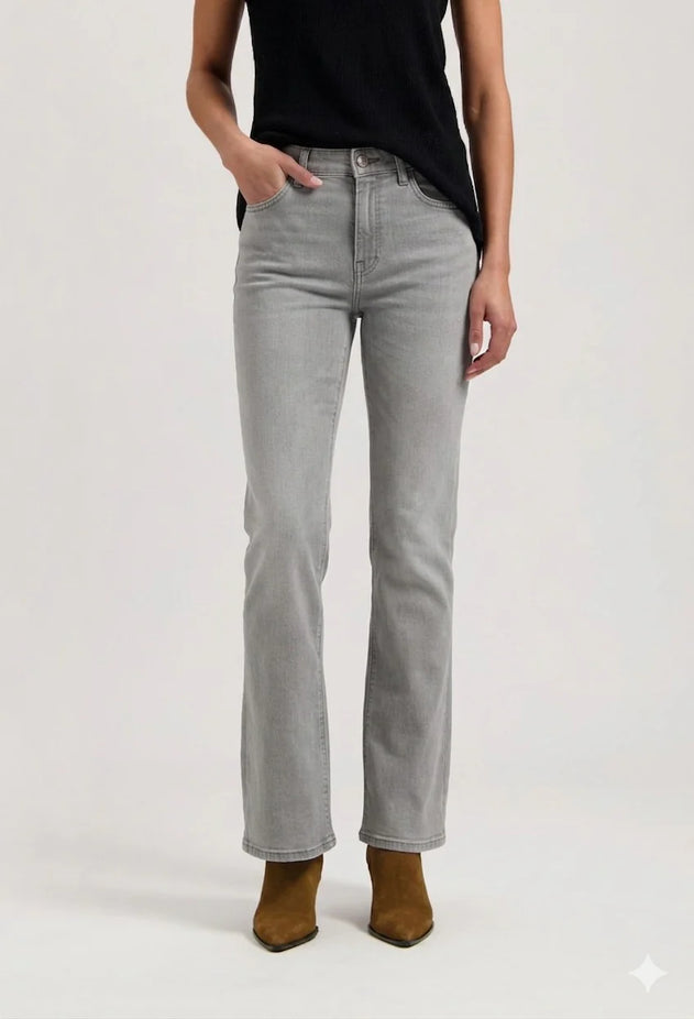 Person wearing light gray jeans and brown boots on a white background