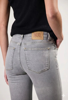 Person wearing gray jeans with a visible brand label on a plain background