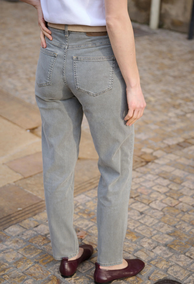 Person wearing light gray jeans on a stone pavement