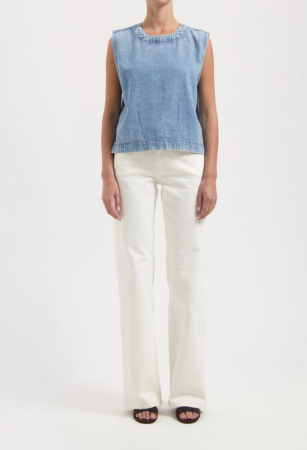 Person wearing a light blue sleeveless top and white pants on a white background