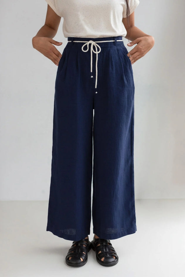 Person wearing navy wide-leg pants with a white top on a plain background