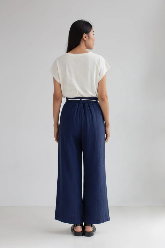 Person wearing a white top and navy wide-leg pants on a plain background