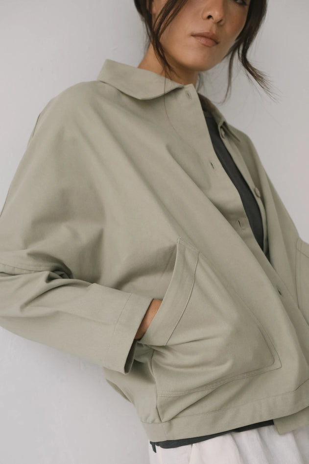 Person wearing a beige jacket on a plain background