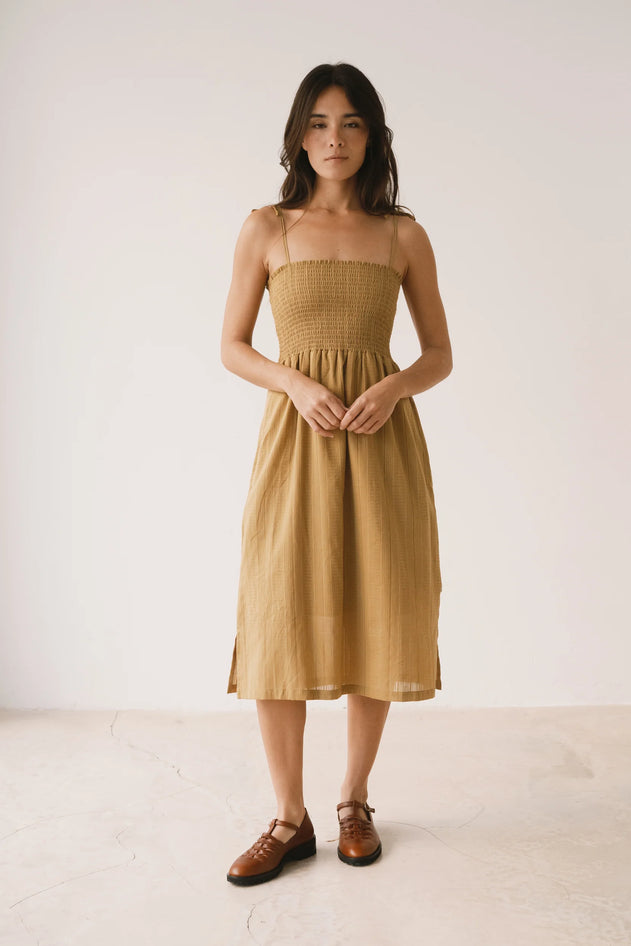 Woman wearing a mustard yellow dress against a white background