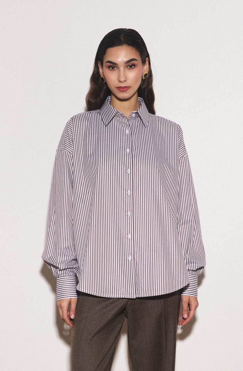 Woman wearing a striped shirt and brown pants on a white background