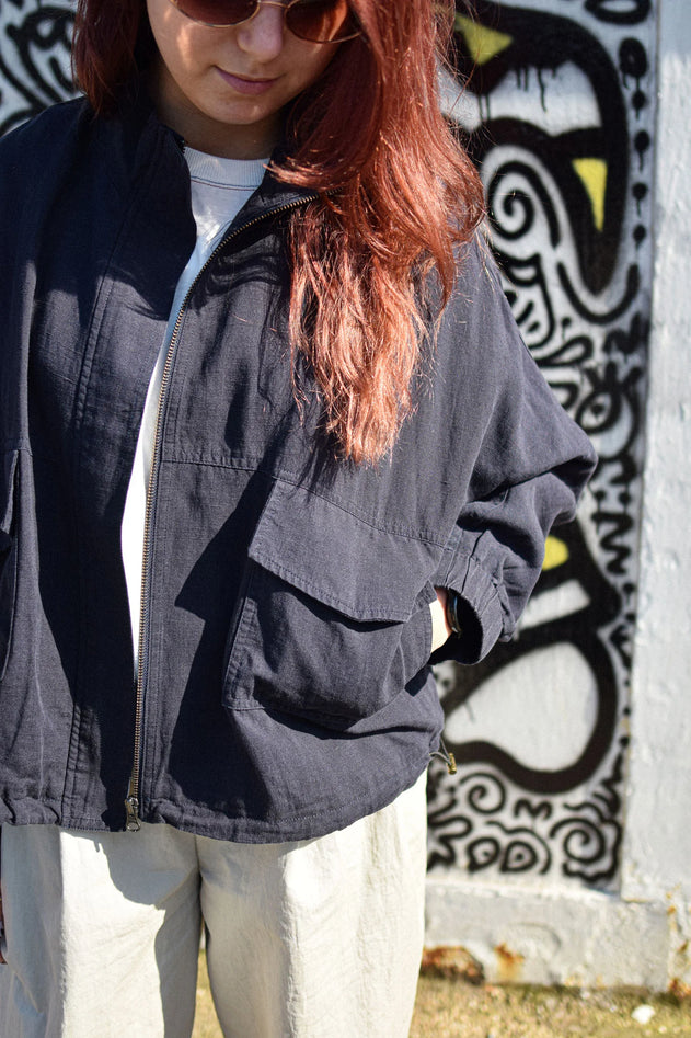 Person wearing a dark jacket in front of a graffiti-covered wall