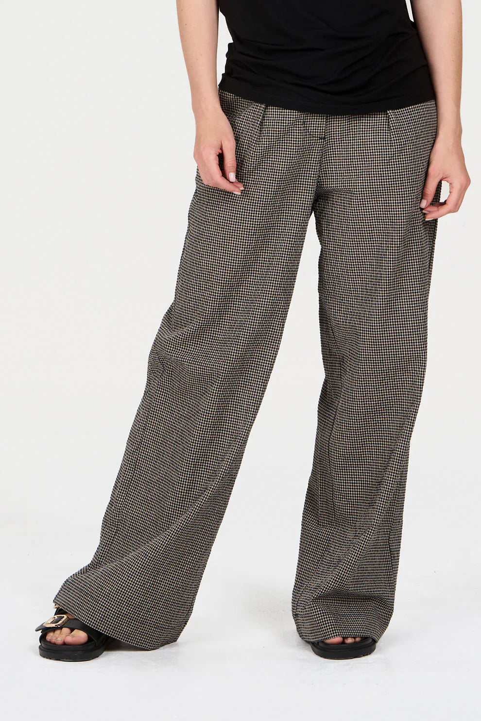 Person wearing wide-leg checkered pants on a white background