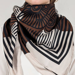 Person wearing a patterned scarf with brown, black, and white design on a plain background