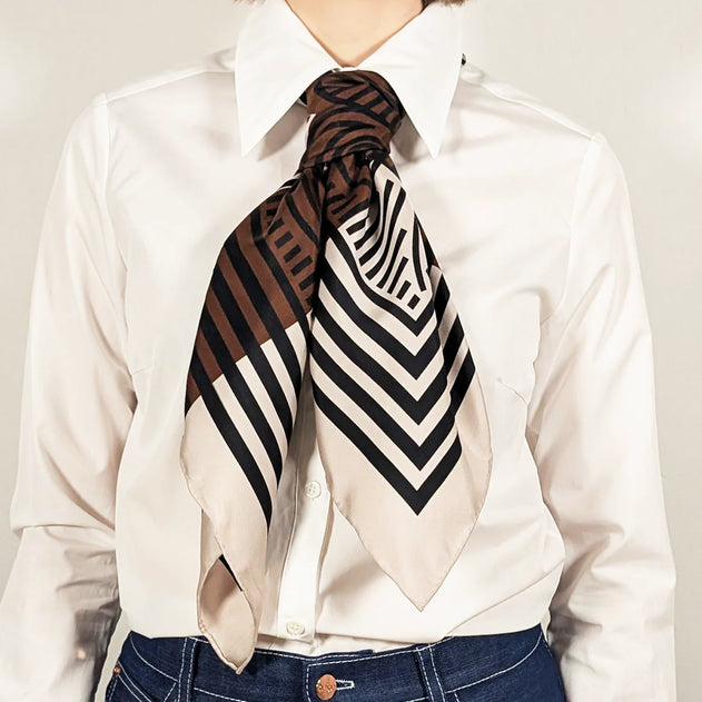 Person wearing a patterned scarf on a plain background