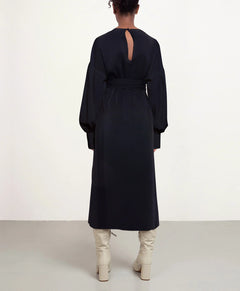 Person wearing a long black dress with a cutout back on a white background