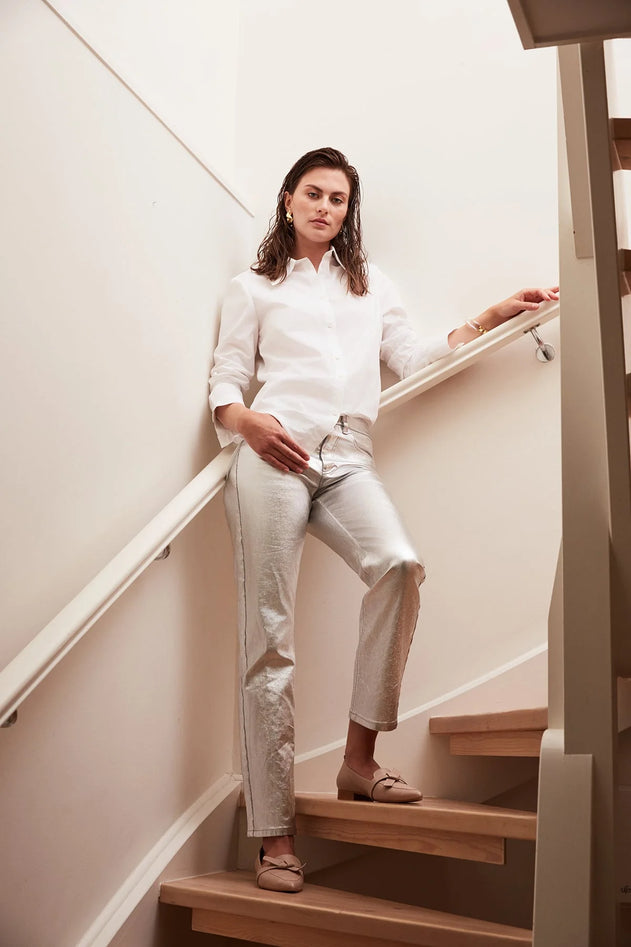 Woman in a white shirt and light pants sitting on a staircase.