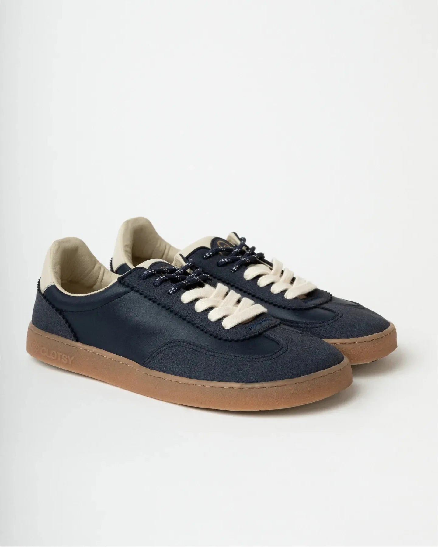 Pair of navy blue sneakers with white laces on a light gray background