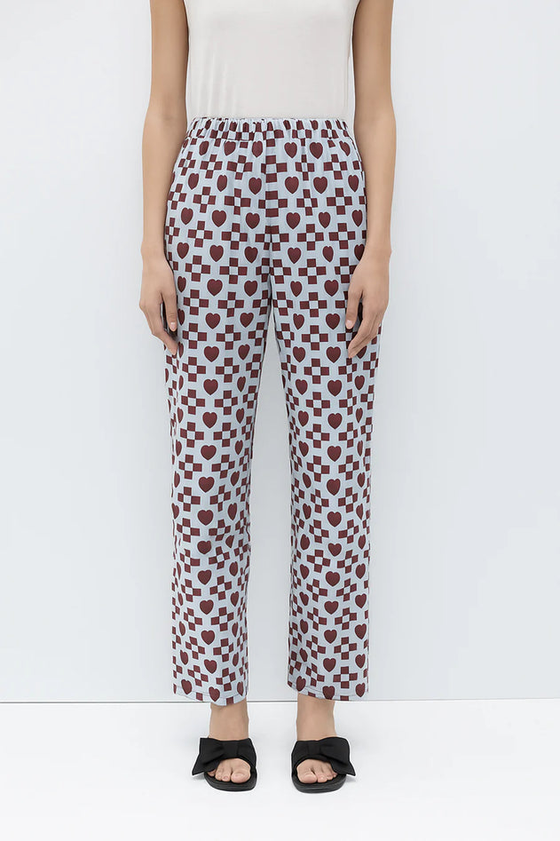 Person wearing a white top and patterned pants on a white background