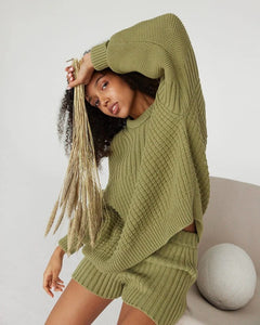 Woman wearing a green knitted outfit with a white background