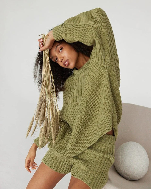 Woman wearing a green knitted outfit with a white background