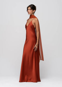 Woman wearing a rust-colored evening gown with cape on a white background
