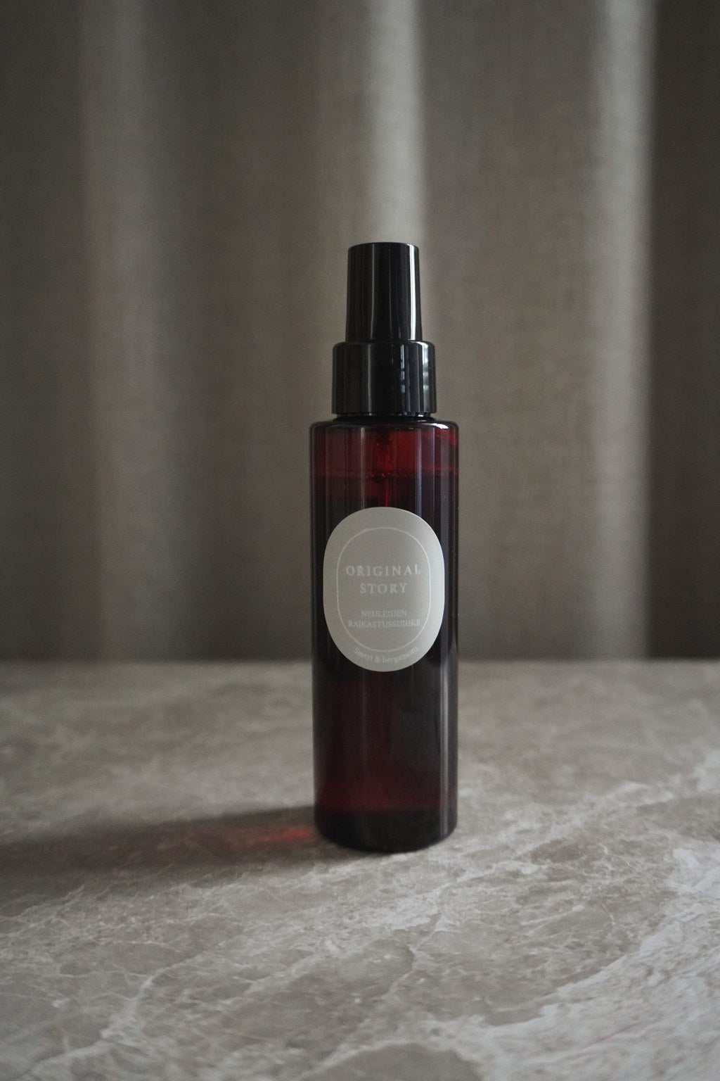Brown spray bottle with a label on a gray surface and background
