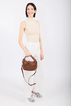 Woman holding a brown handbag against a white background
