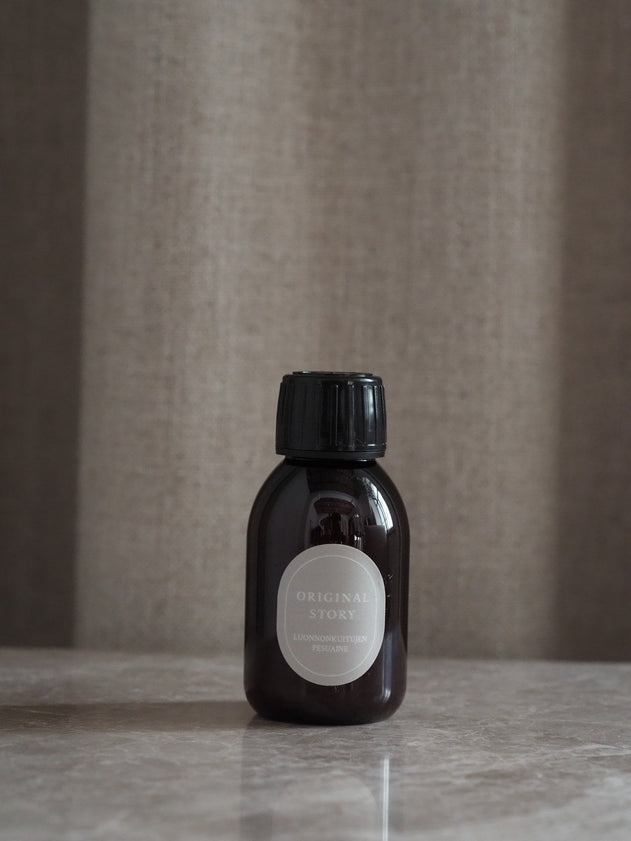 Small brown bottle with a black cap on a reflective surface against a neutral background