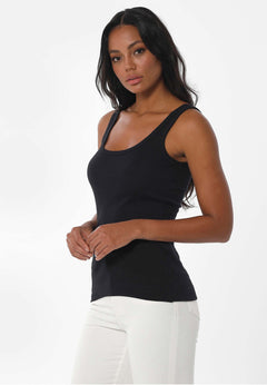 Woman wearing a black tank top and white pants on a white background